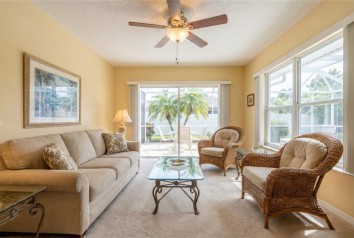Bright living room with beige sofa, wicker chairs, and patio view in a New Port Richey, Florida home.